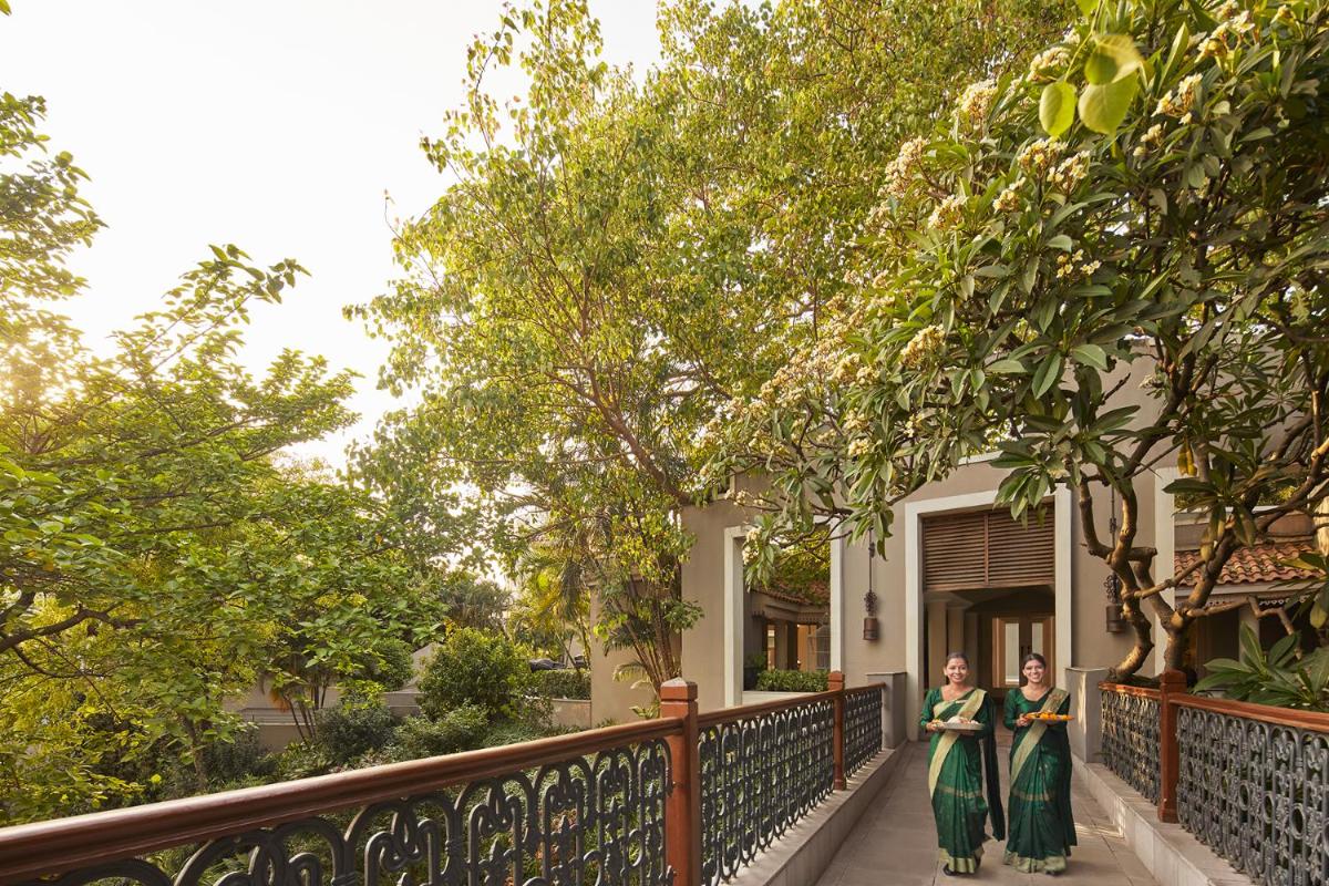 two women standing in front of a house with trees at Raajkutir - IHCL SeleQtions in Kolkata