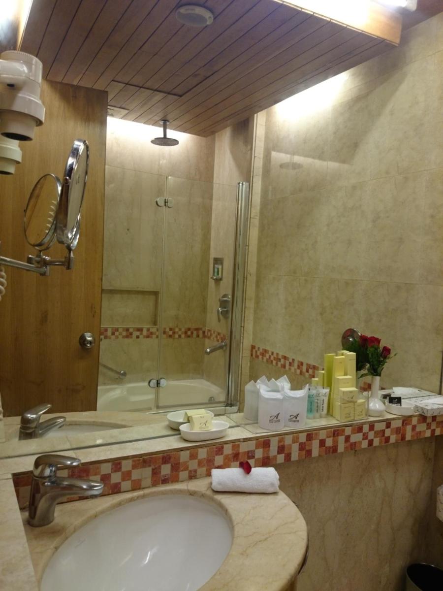 a bathroom with a sink and a shower and a mirror at The Ashok, New Delhi in New Delhi a bathroom with a sink and a shower and a mirror at The Ashok, New Delhi in New Delhi