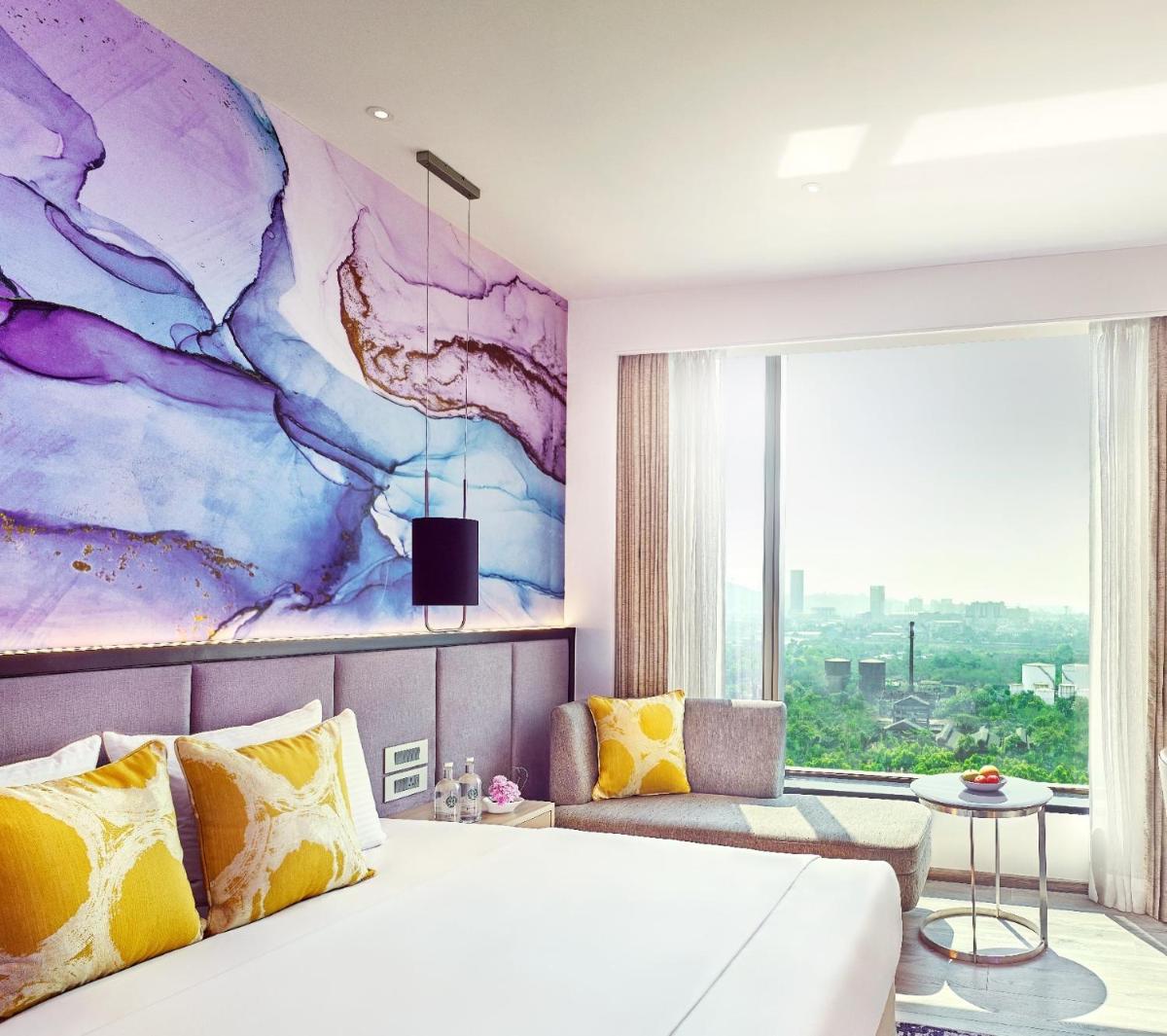 a bedroom with a bed and a large window at Vivanta Navi Mumbai Turbhe in Navi Mumbai