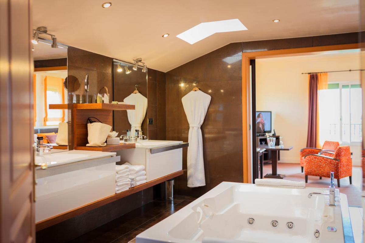 une salle de bain avec deux lavabos et un grand miroir dans l'établissement Palmyra Golf Hotel & Spa, au Cap d'Agde