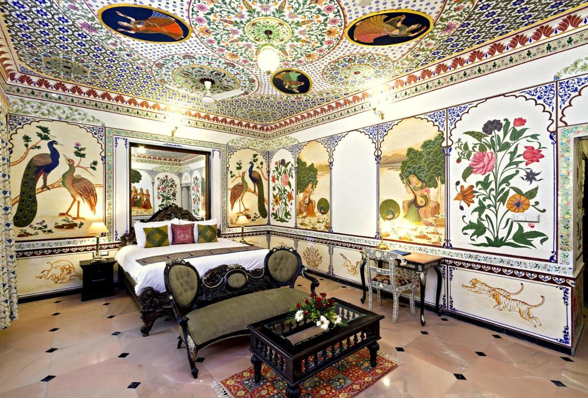 a bedroom with a bed and paintings on the walls at Chunda Palace in Udaipur