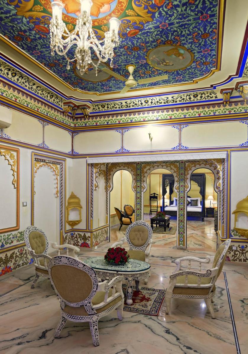 a room with a table and chairs and a ceiling at Chunda Palace in Udaipur