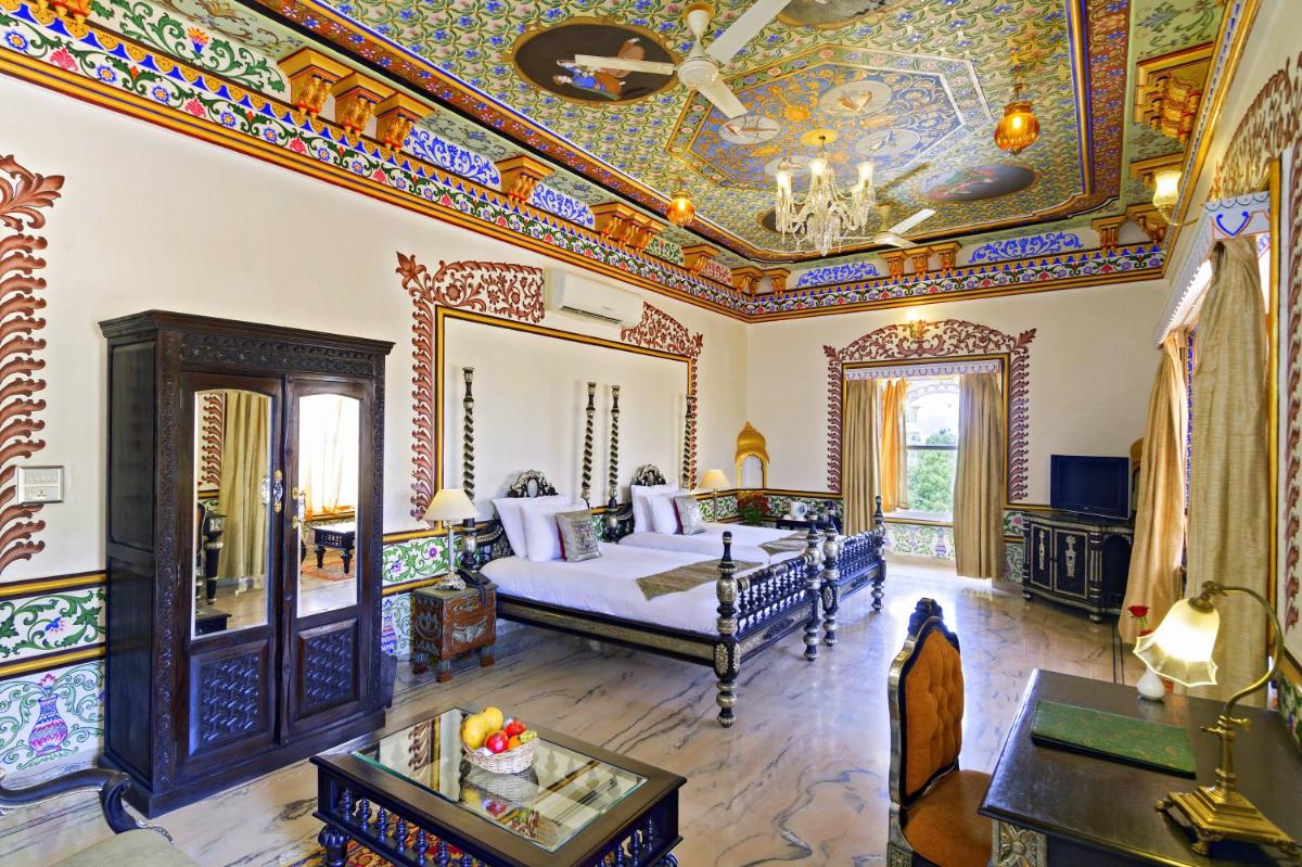 a large room with a bed and a mirror at Chunda Palace in Udaipur