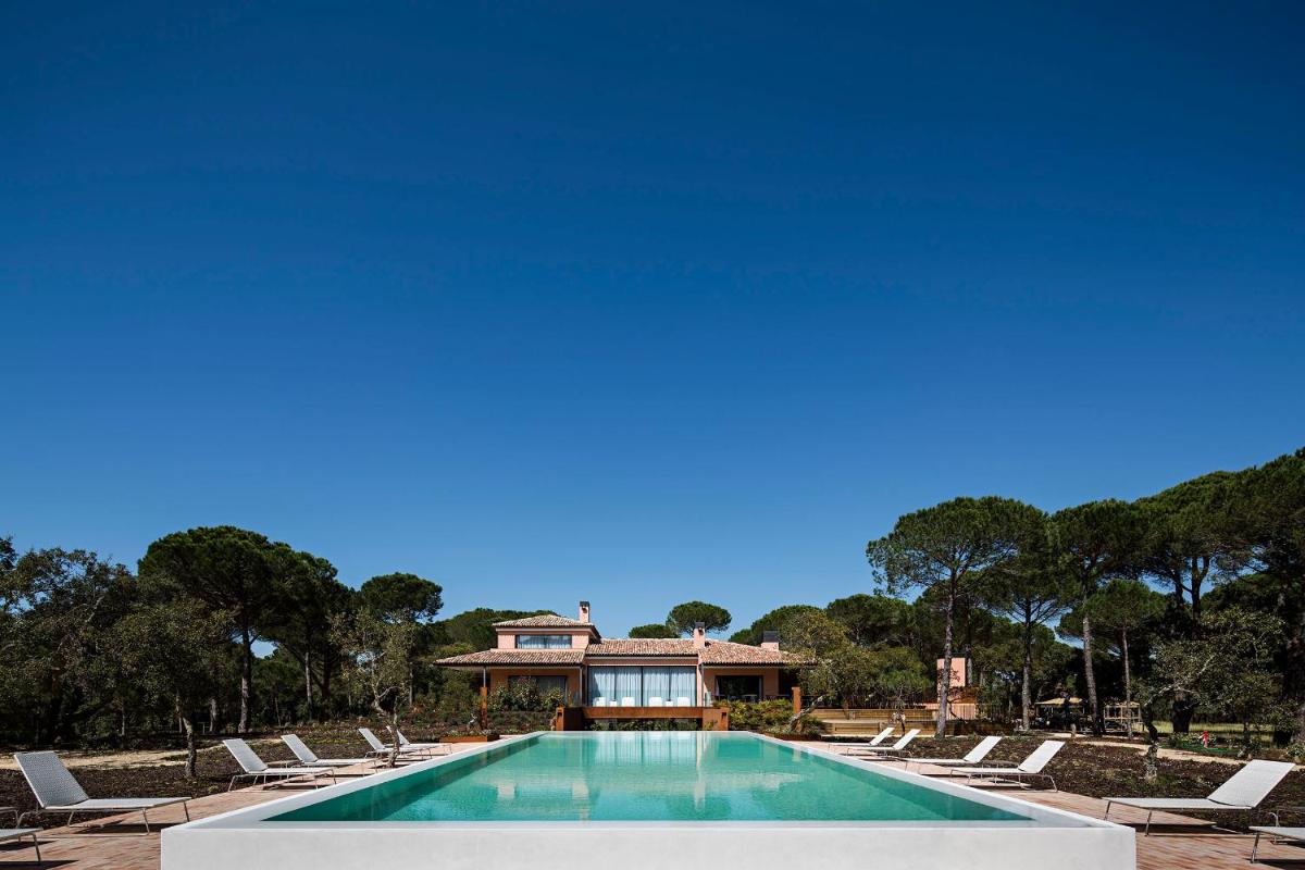 uma piscina com espreguiçadeiras e uma casa em Sublime Comporta Country Retreat & SPA na Comporta