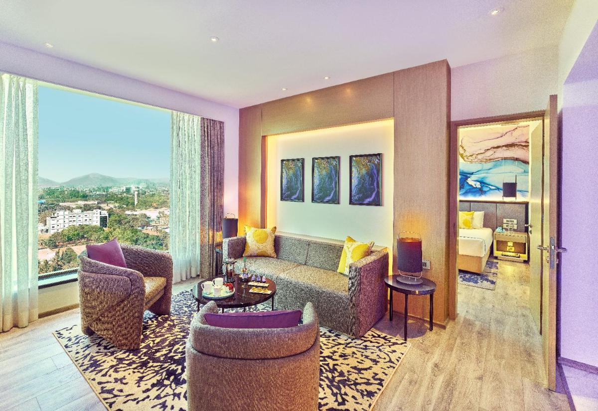 a living room with a couch and chairs in a hotel room at Vivanta Navi Mumbai Turbhe in Navi Mumbai
