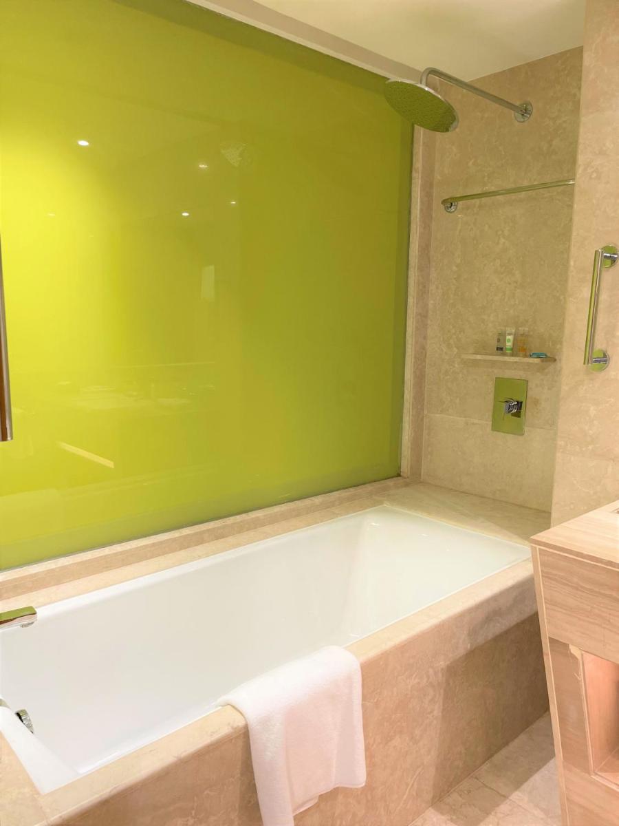 a bath tub in a bathroom with a green wall at Hyatt Centric Janakpuri New Delhi in New Delhi