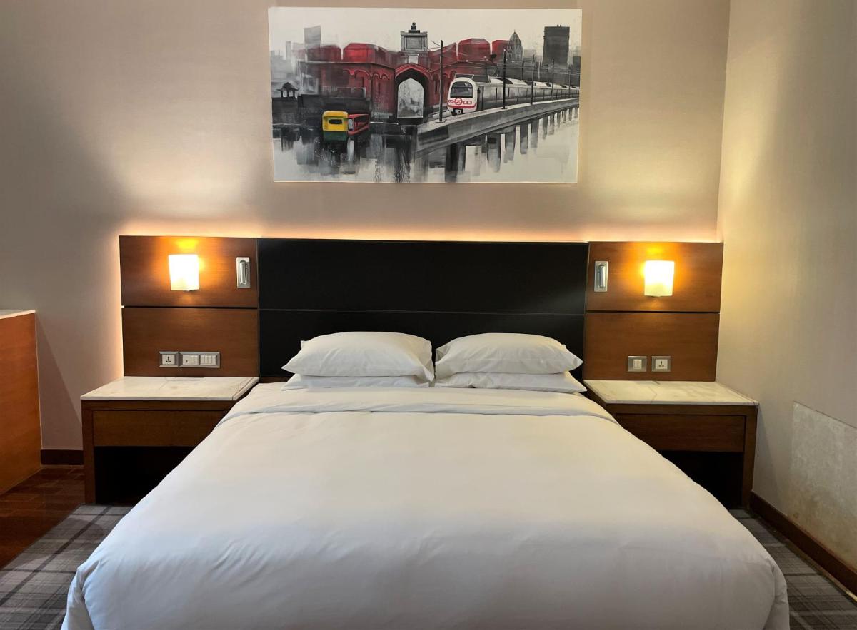 a bedroom with a large white bed and a painting at Hyatt Centric Janakpuri New Delhi in New Delhi