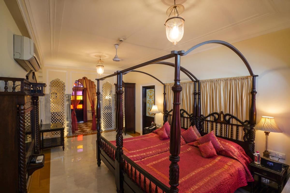 a bedroom with a large canopy bed with red sheets at Shahpura House in Jaipur