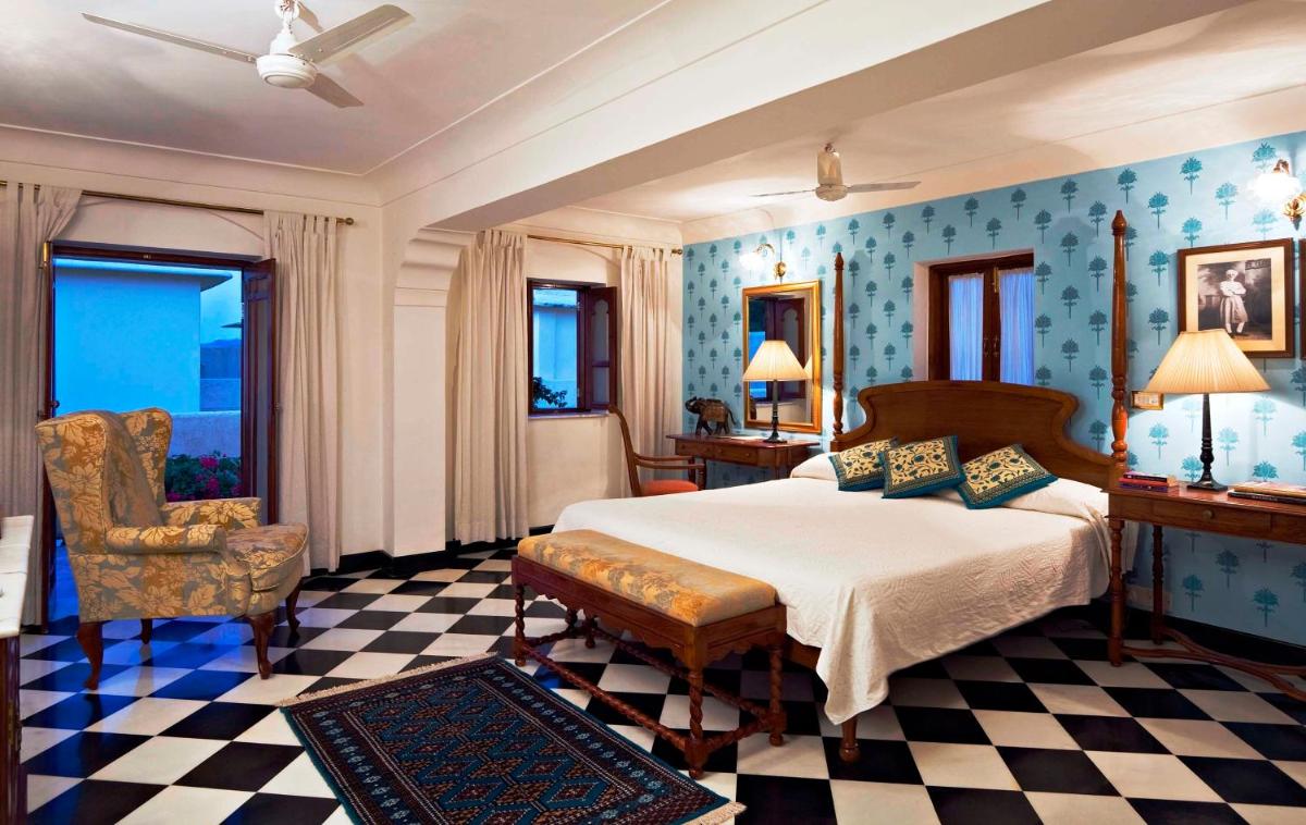 a bedroom with a bed and a chair at Samode Haveli in Jaipur