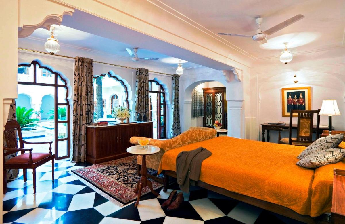 a bedroom with an orange bed and a table and chairs at Samode Haveli in Jaipur