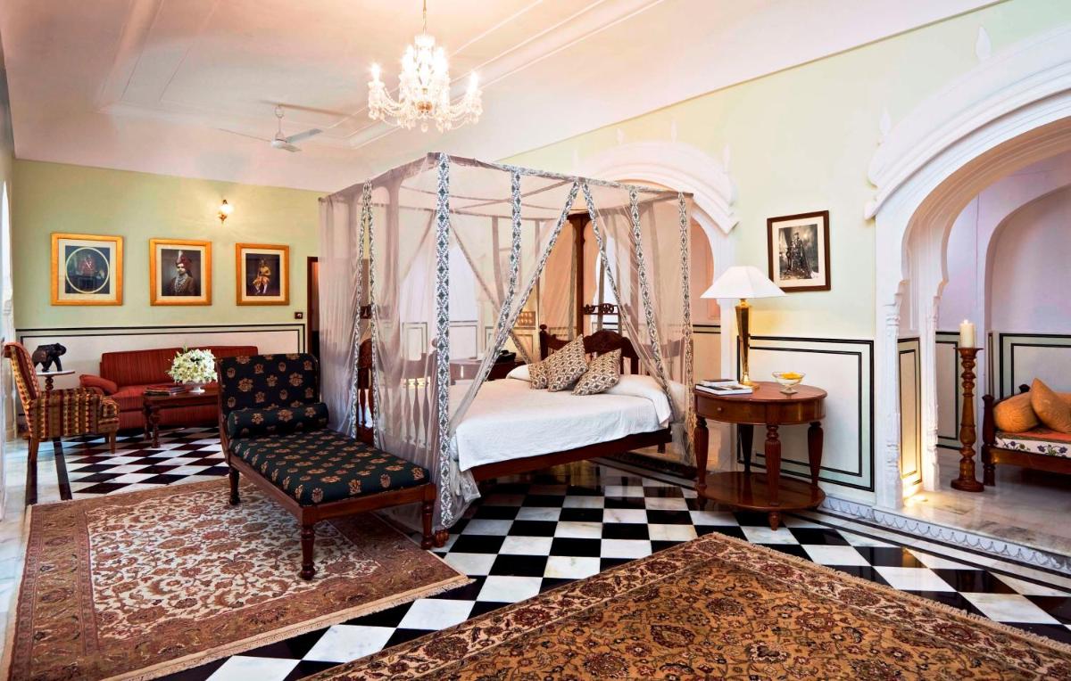 a bedroom with a canopy bed and a chair at Samode Haveli in Jaipur