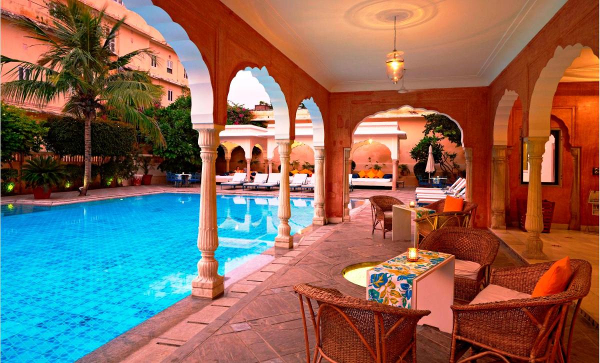 a pool in a building with chairs and a table at Samode Haveli in Jaipur