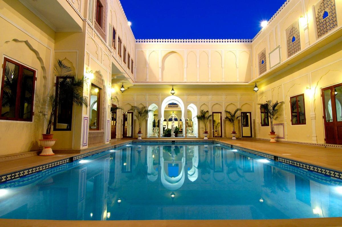 a large swimming pool in a building with a swimming poolvisorvisor at The Raj Palace (Small Luxury Hotels of the World) in Jaipur