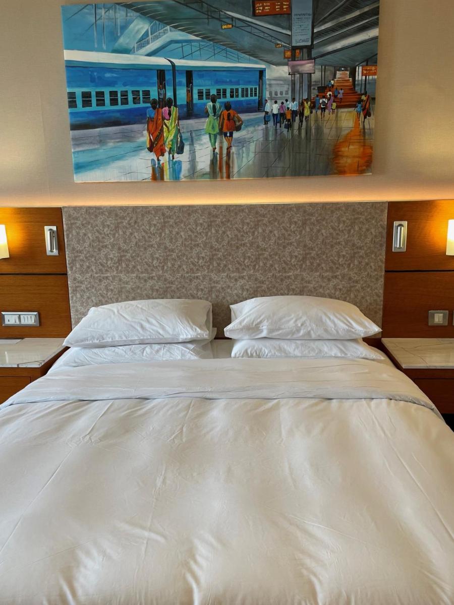 a large white bed with a painting on the wall at Hyatt Centric Janakpuri New Delhi in New Delhi