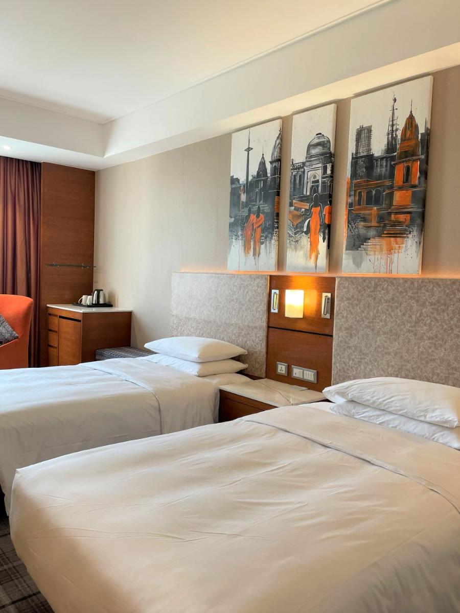 a hotel room with two beds and paintings on the wall at Hyatt Centric Janakpuri New Delhi in New Delhi