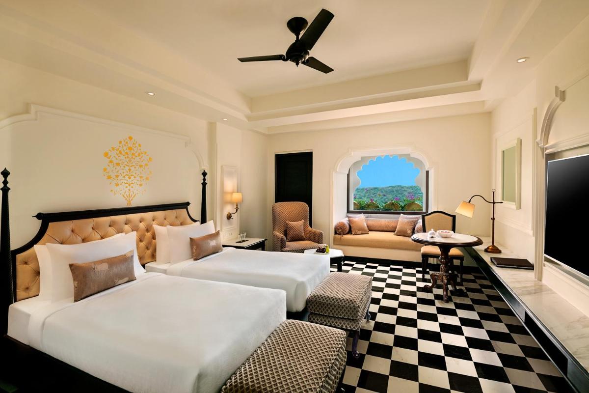 a bedroom with two beds and a couch and a window at Aurika, Udaipur - Luxury by Lemon Tree Hotels in Udaipur