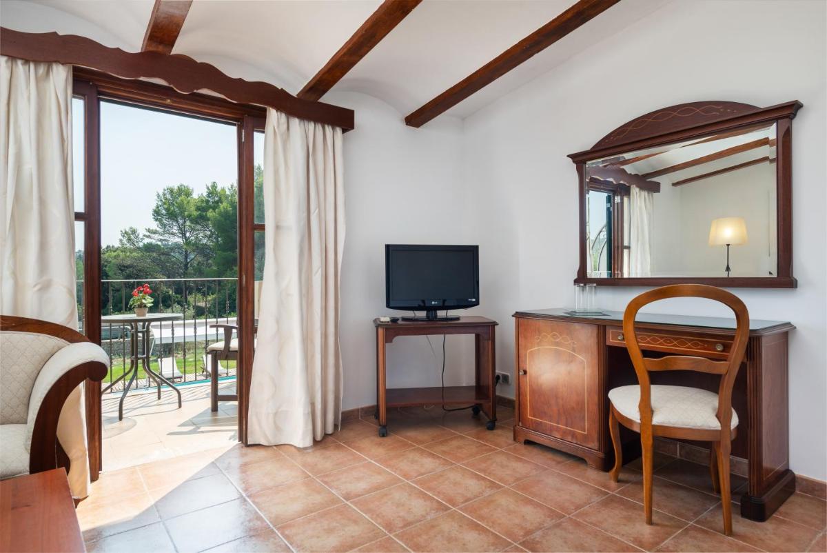 Habitación con escritorio, TV y espejo. en Monnaber Nou Finca Hotel & Spa, en Campanet