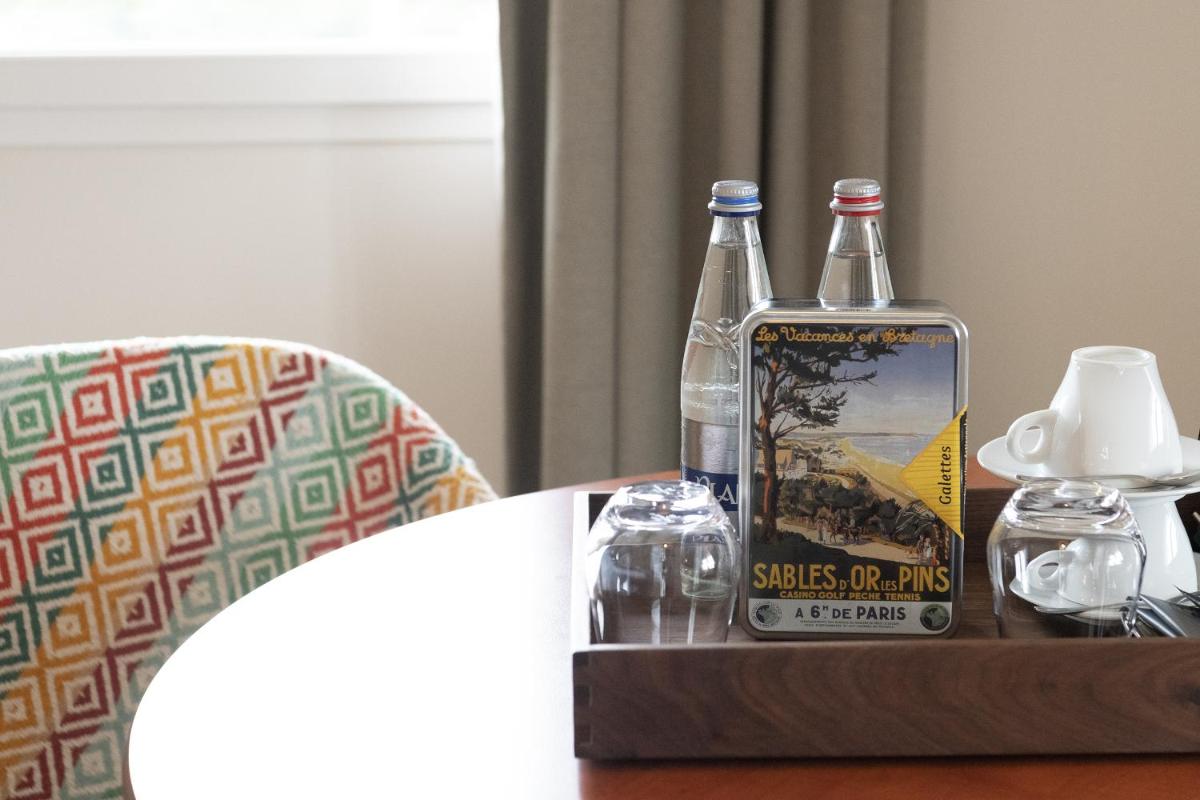 une table avec deux bouteilles d'alcool et un livre dans l'établissement Hotel De Diane, aux Sables-dʼOr-les-Pins