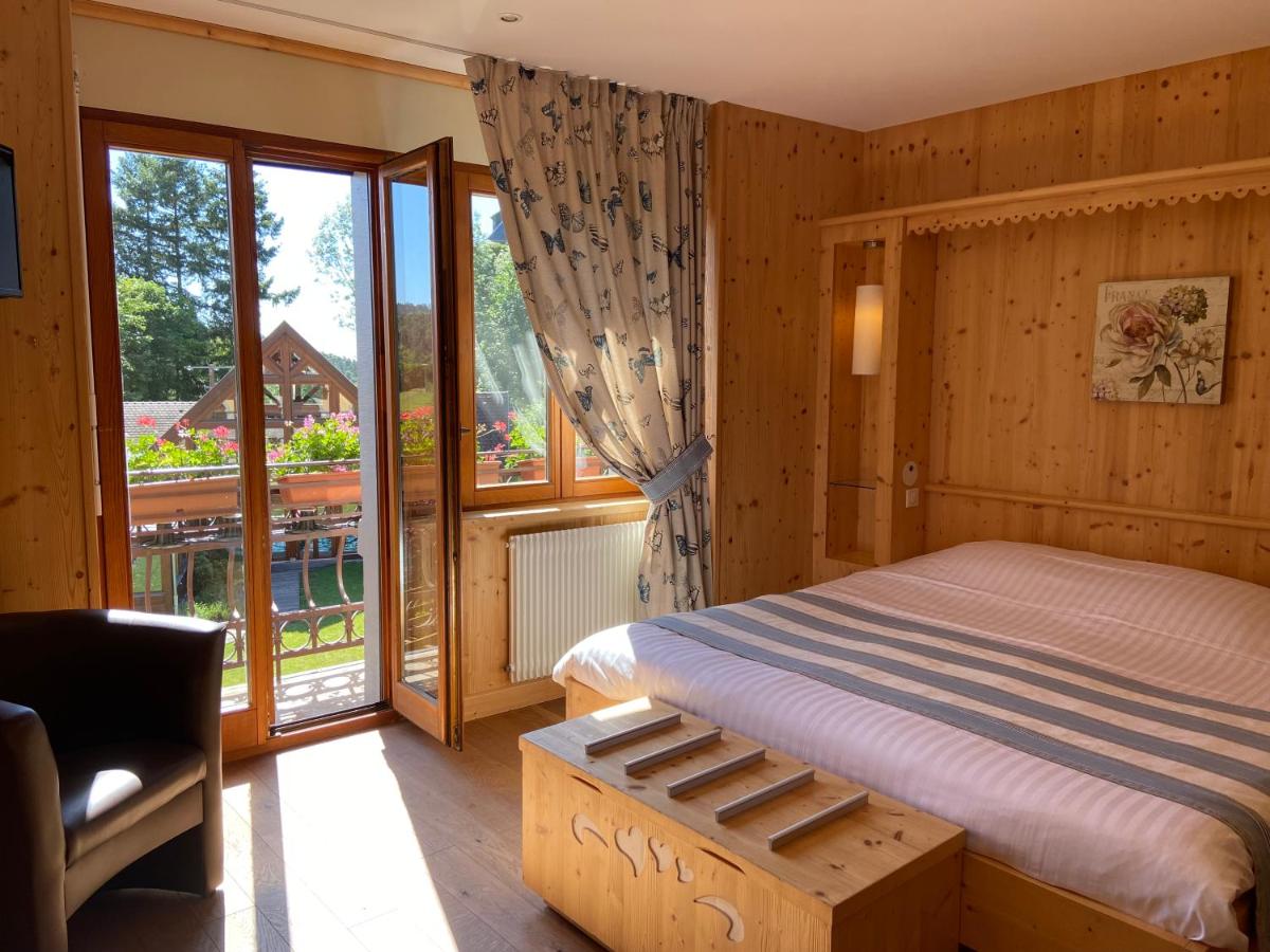 une chambre avec un lit et une grande fenêtre dans l'établissement LE CLOS DES SOURCES Hôtel & Spa, à Thannenkirch