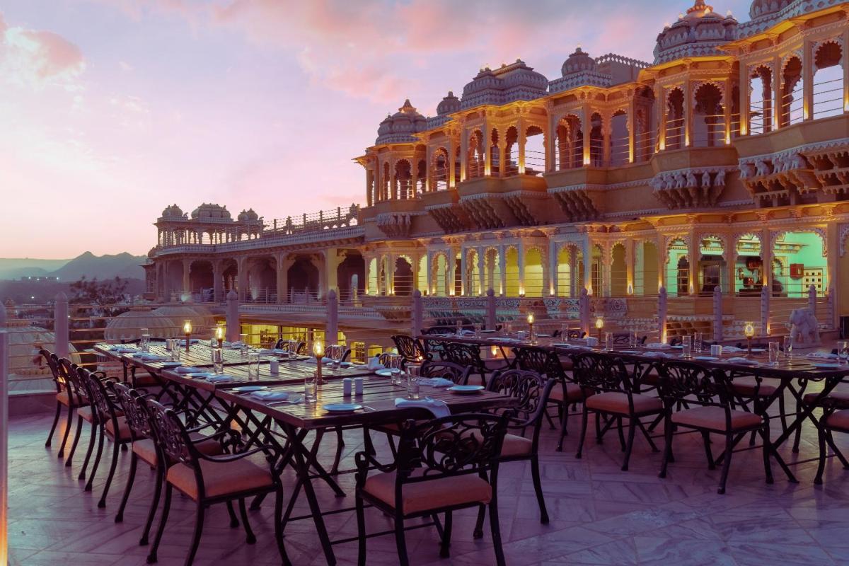 a long table with chairs in front of a building at Chunda Palace in Udaipur