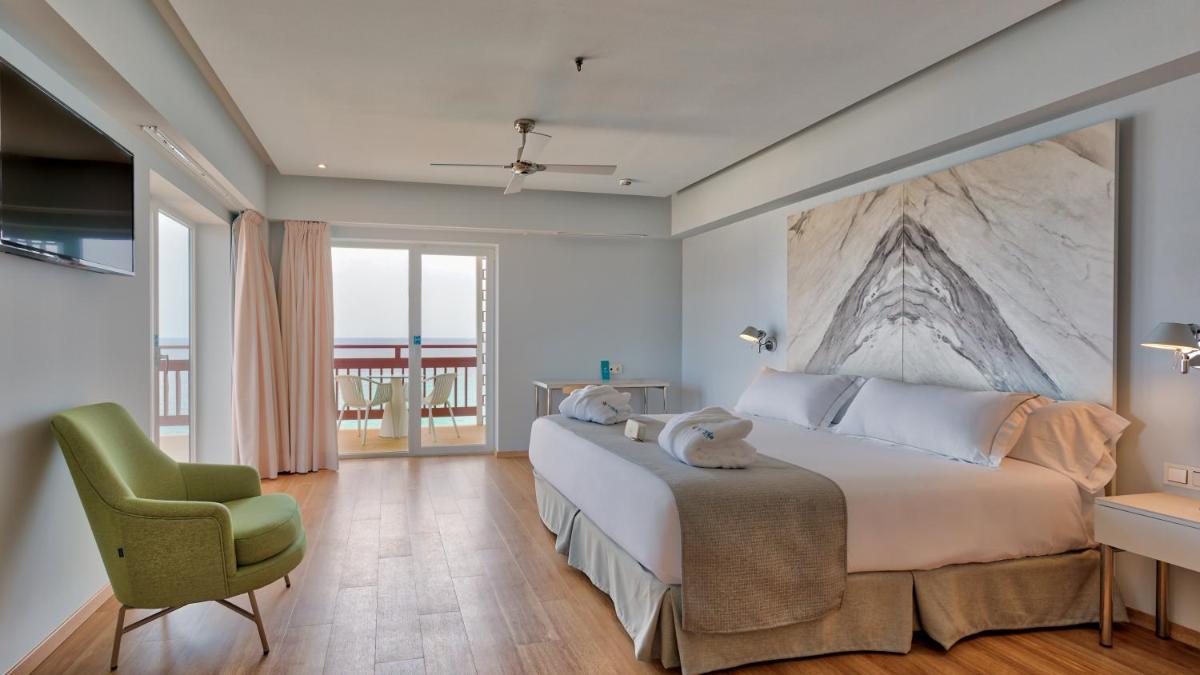 1 dormitorio con 1 cama grande y 1 silla verde en Talayot - Adults Only, en Cala Millor