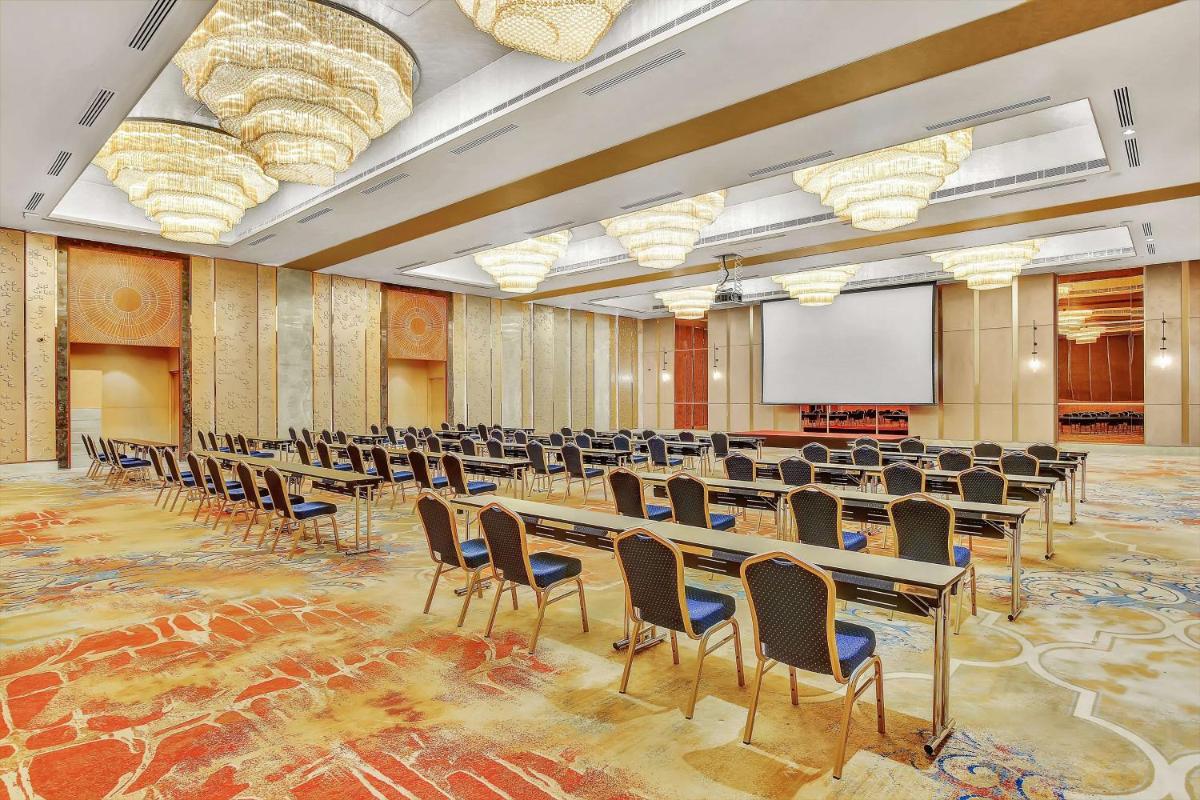 a conference room with tables and chairs and a screen at Radisson RED Chandigarh Mohali in Chandīgarh