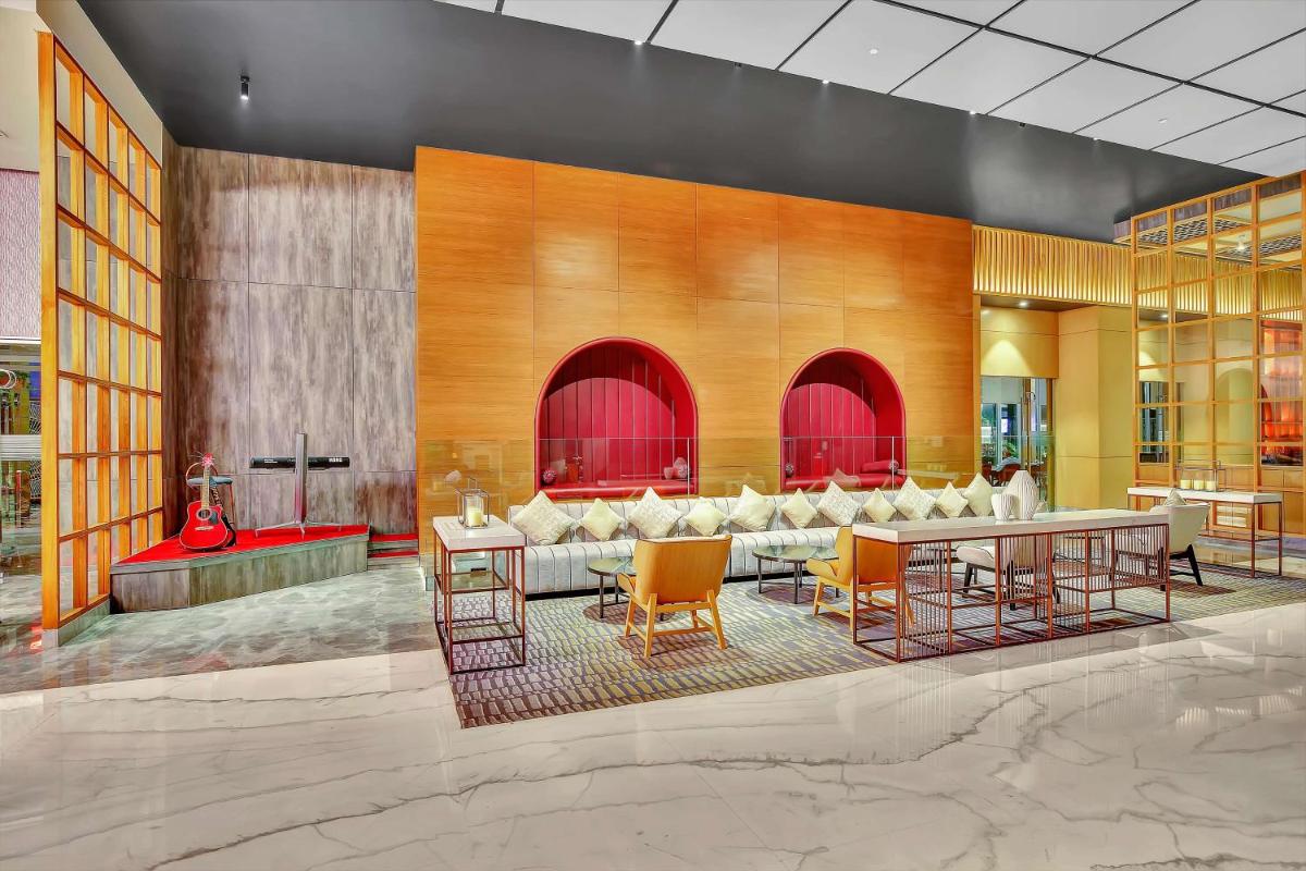 a lobby with tables and chairs in a building at Radisson RED Chandigarh Mohali in Chandīgarh