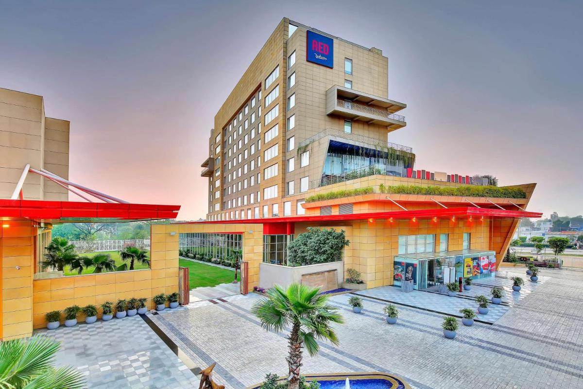 a hotel building with a palm tree in front of it at Radisson RED Chandigarh Mohali in Chandīgarh