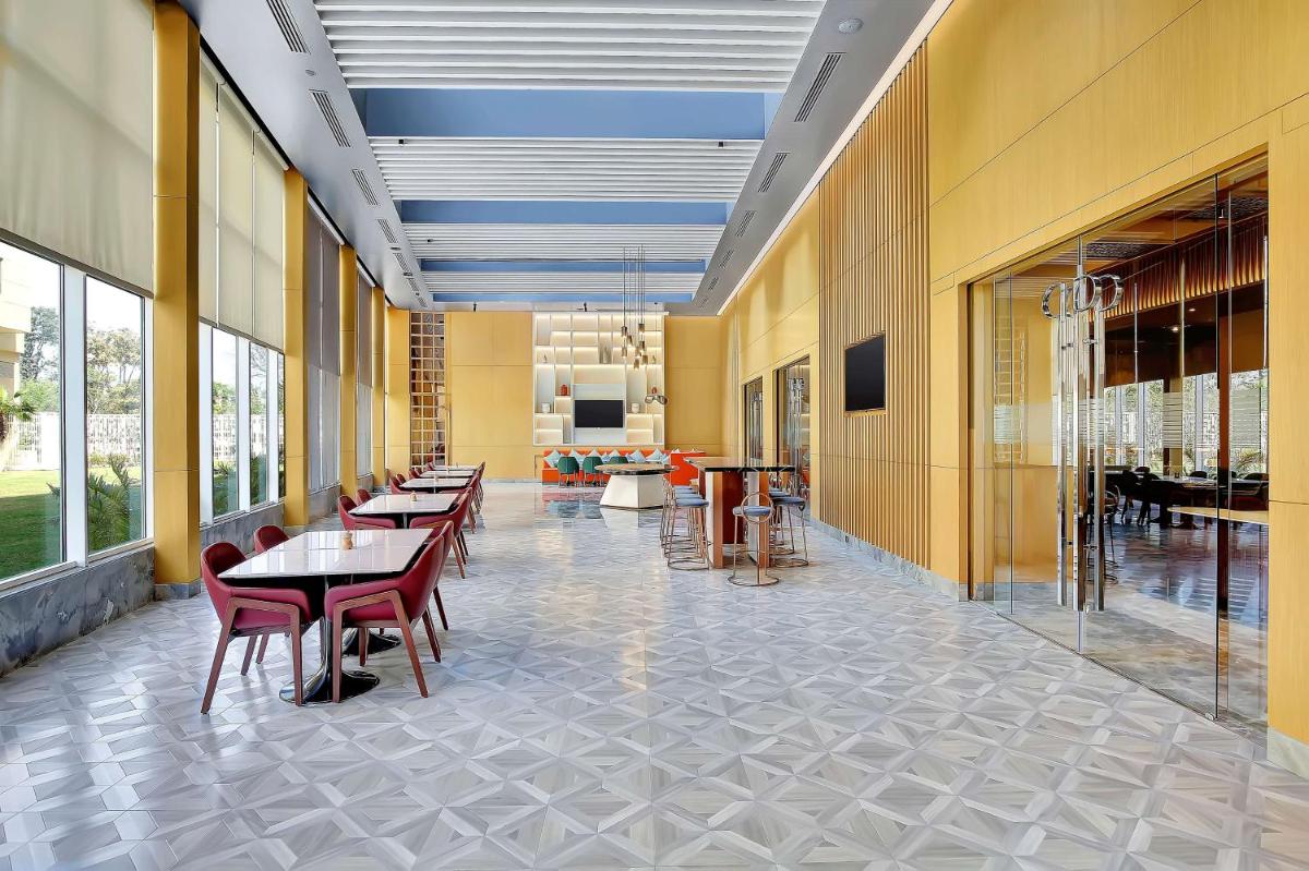 a hallway with tables and chairs in a building at Radisson RED Chandigarh Mohali in Chandīgarh