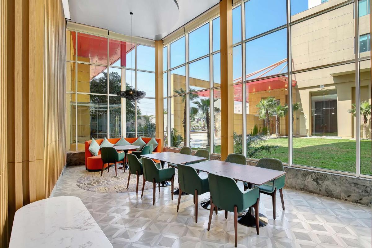 a cafeteria with tables and chairs and windows at Radisson RED Chandigarh Mohali in Chandīgarh