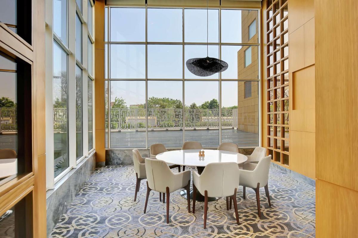 a dining room with a table and chairs and a large window at Radisson RED Chandigarh Mohali in Chandīgarh