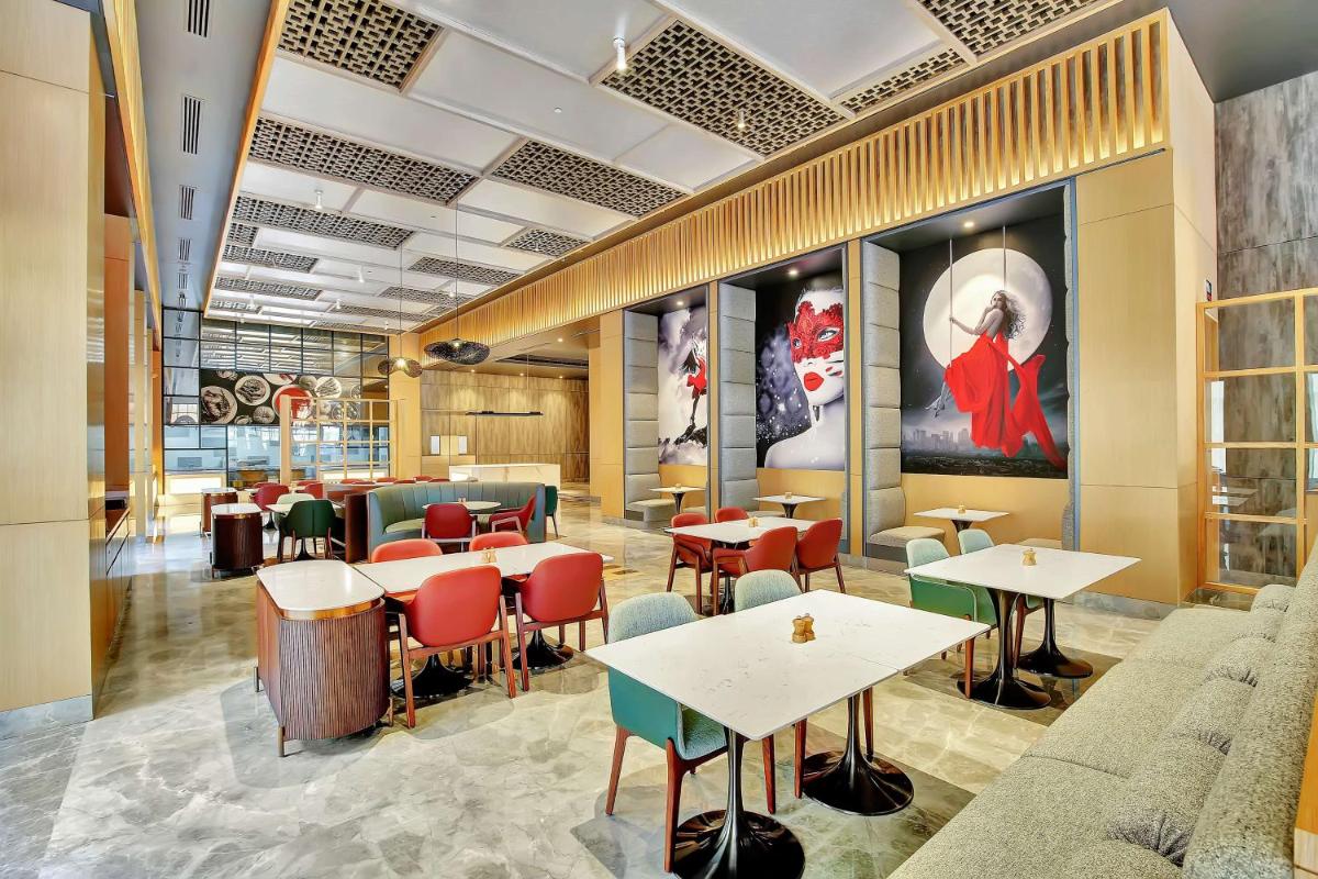a restaurant with tables and chairs in a room at Radisson RED Chandigarh Mohali in Chandīgarh
