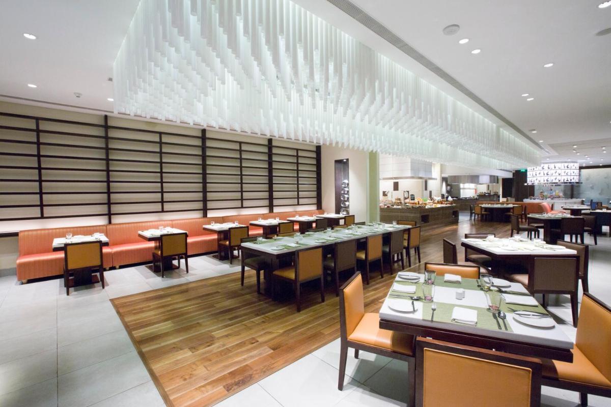 a dining room with tables and chairs in a restaurant at Holiday Inn Chennai OMR IT Expressway by IHG in Chennai