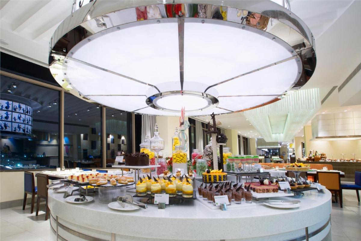 a large chandelier hangs over a buffet of food at Holiday Inn Chennai OMR IT Expressway by IHG in Chennai