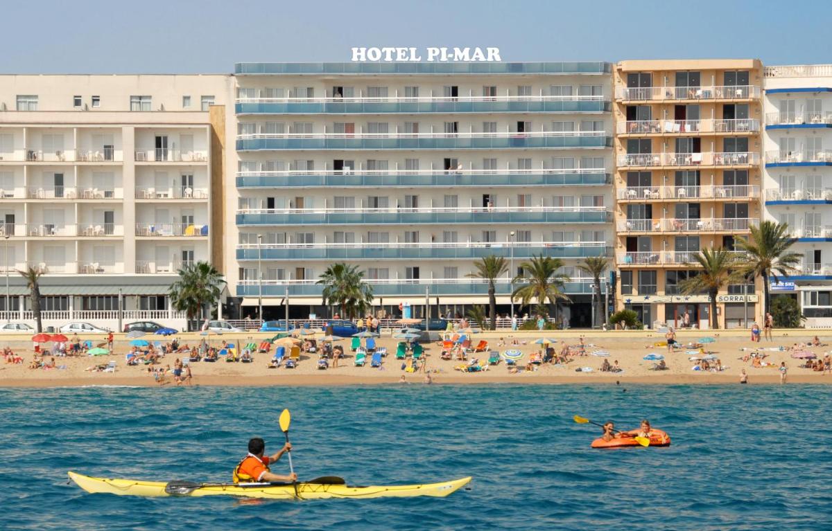 Un hombre en un kayak en el agua frente a una playa. en Hotel Pimar & Spa, en Blanes