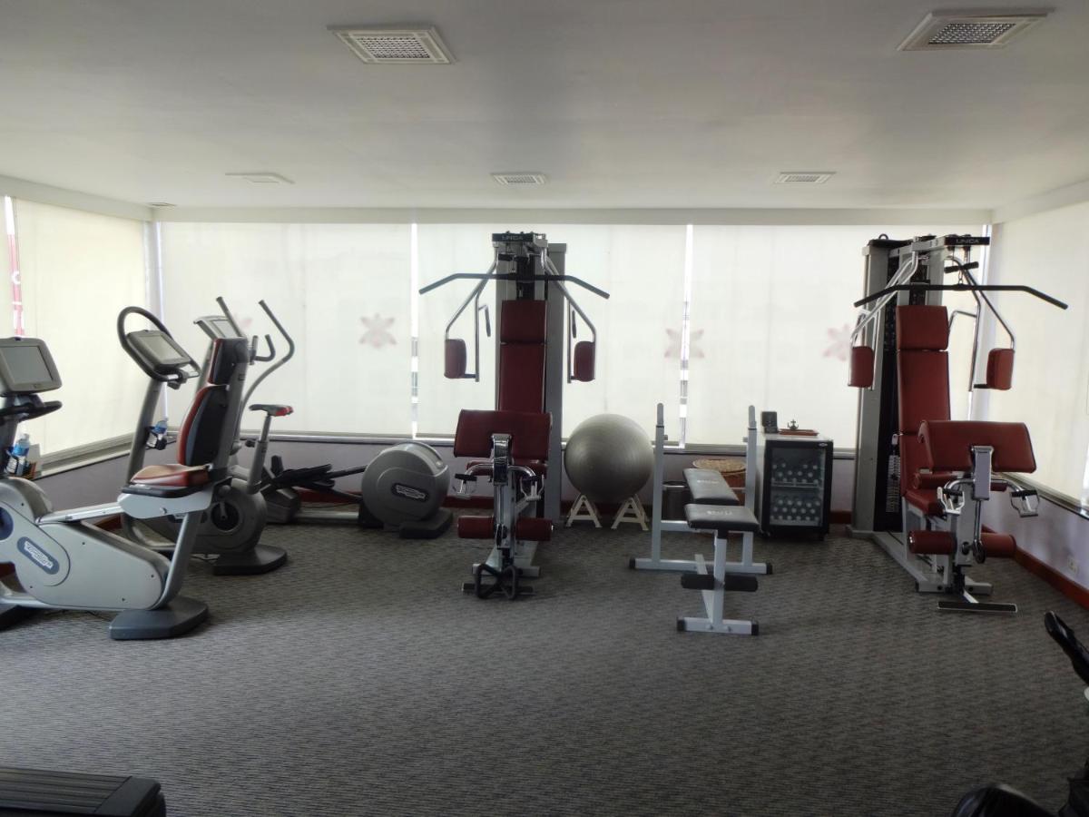 a gym with several treadmills and exercise machines at Hotel Royal Orchid Bangalore in Bengaluru
