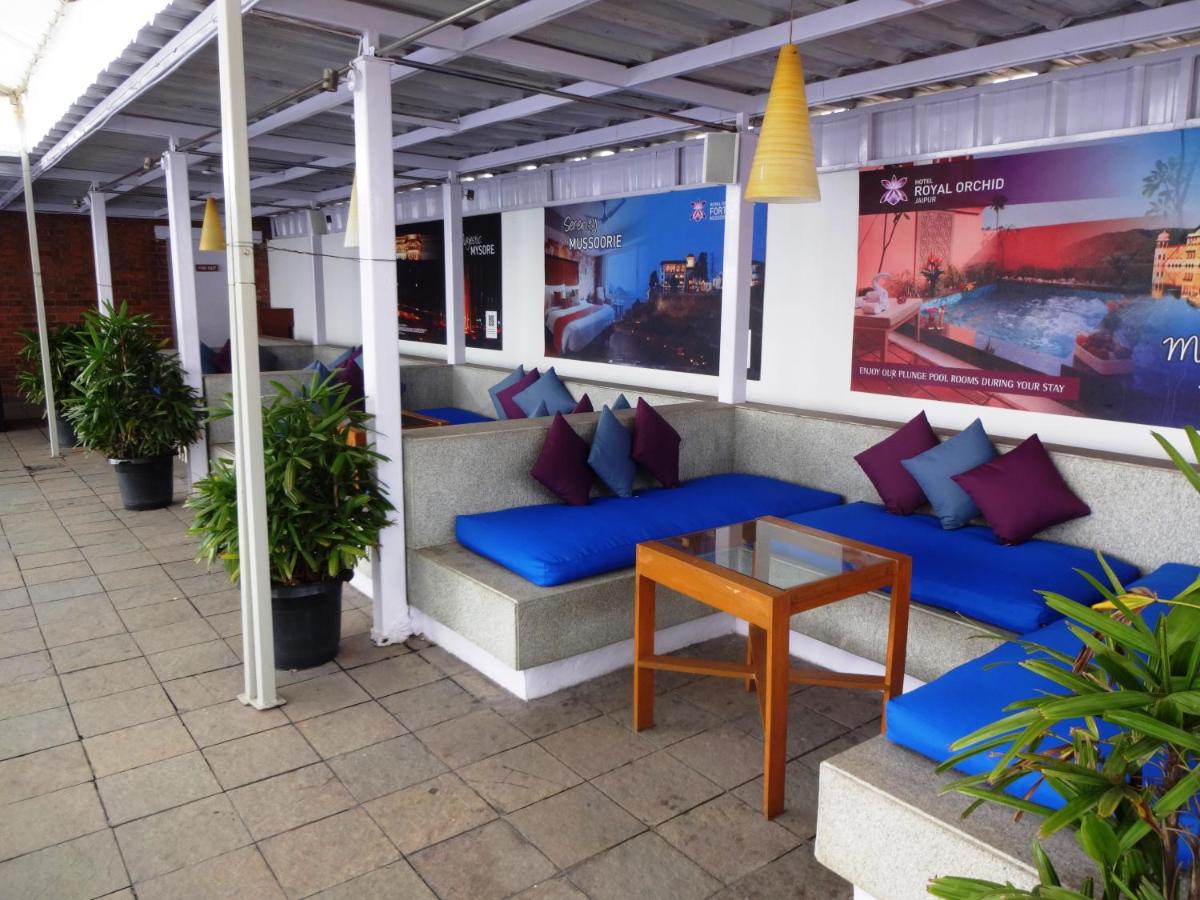 a patio with blue couches and a table at Hotel Royal Orchid Bangalore in Bengaluru
