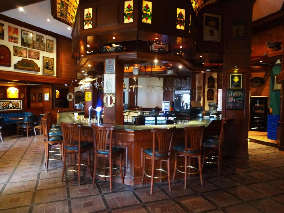 a bar in a restaurant with wooden bar stools at Hotel Royal Orchid Bangalore in Bengaluru
