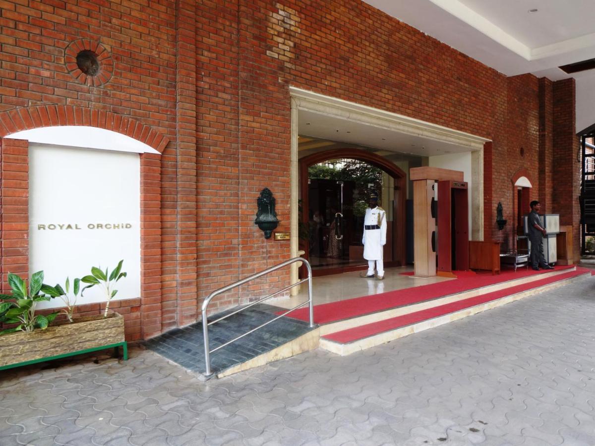 a woman standing outside of a brick building at Hotel Royal Orchid Bangalore in Bengaluru