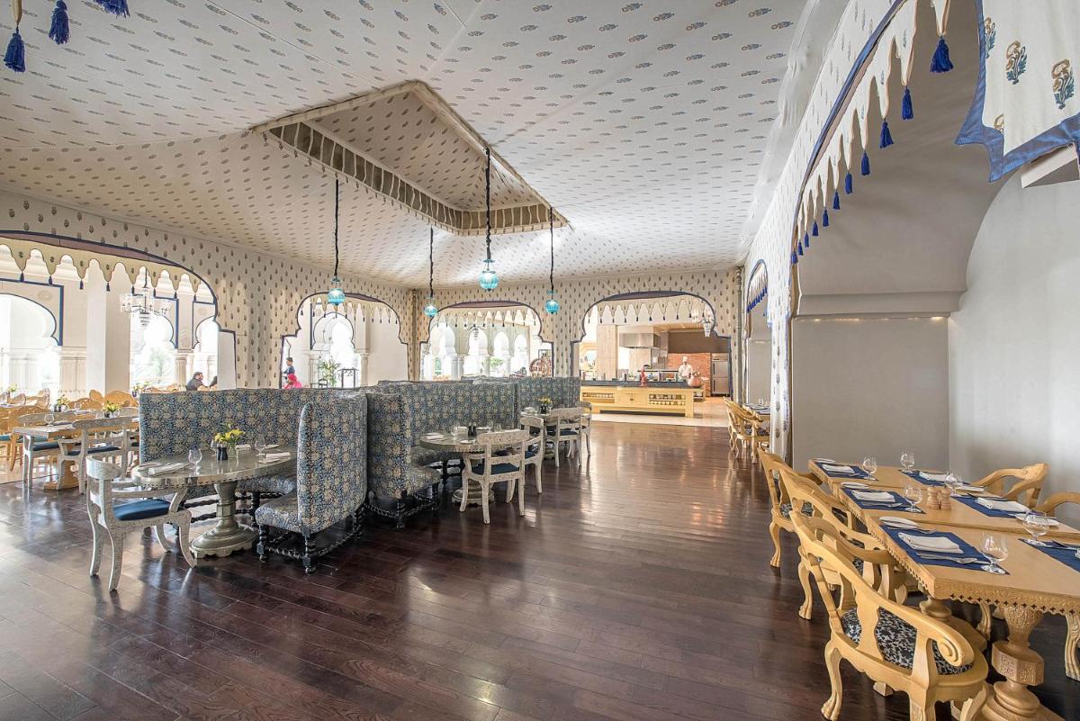 a restaurant with tables and chairs in a room at Fairmont Jaipur in Jaipur
