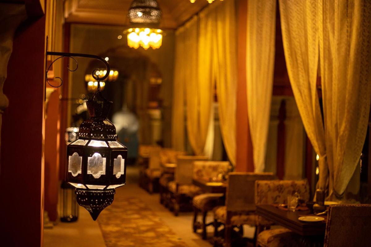 a room with curtains and a lamp with tables and chairs at Fairmont Jaipur in Jaipur
