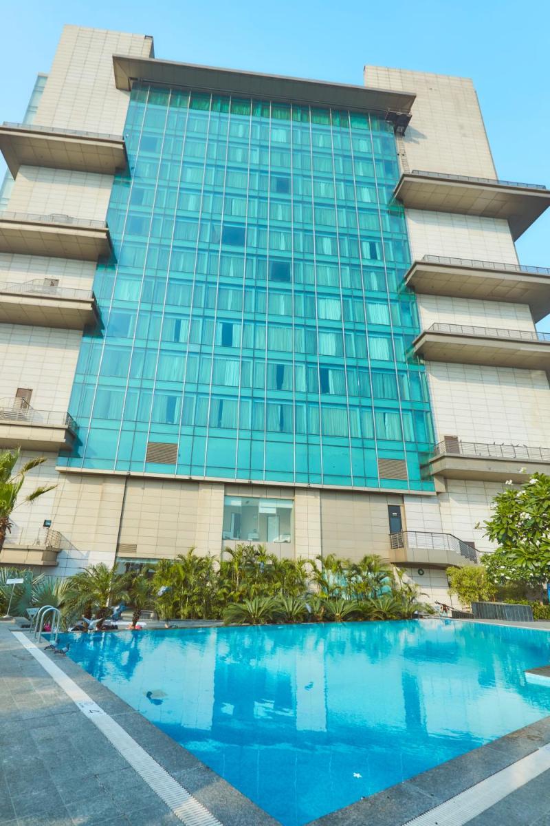a building with a swimming pool in front of it at Crowne Plaza New Delhi Rohini by IHG in New Delhi a building with a swimming pool in front of it at Crowne Plaza New Delhi Rohini by IHG in New Delhi
