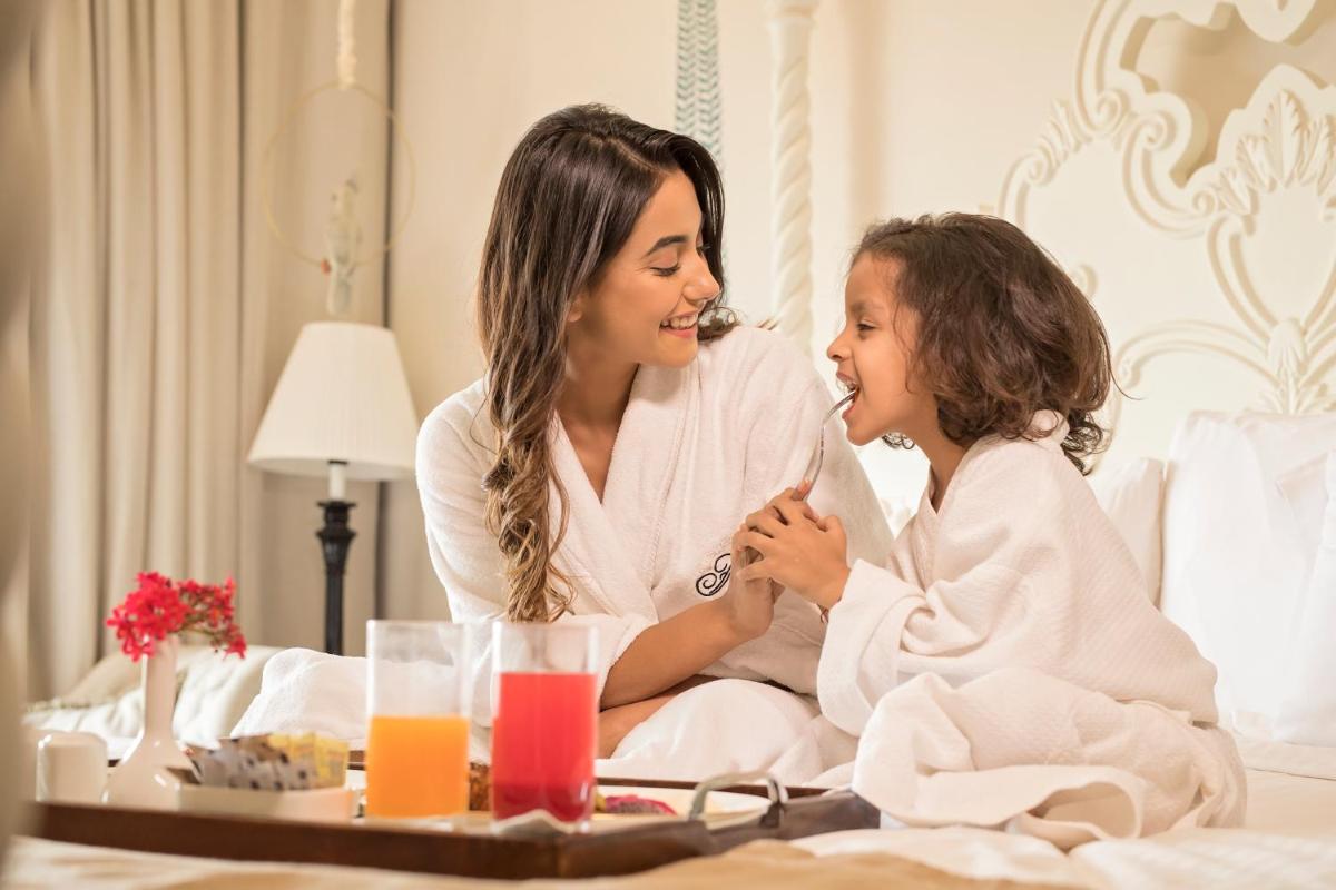 a woman and a little girl sitting on a bed at Fairmont Jaipur in Jaipur