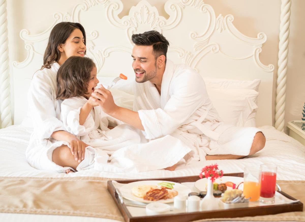 a family sitting on a bed eating food at Fairmont Jaipur in Jaipur
