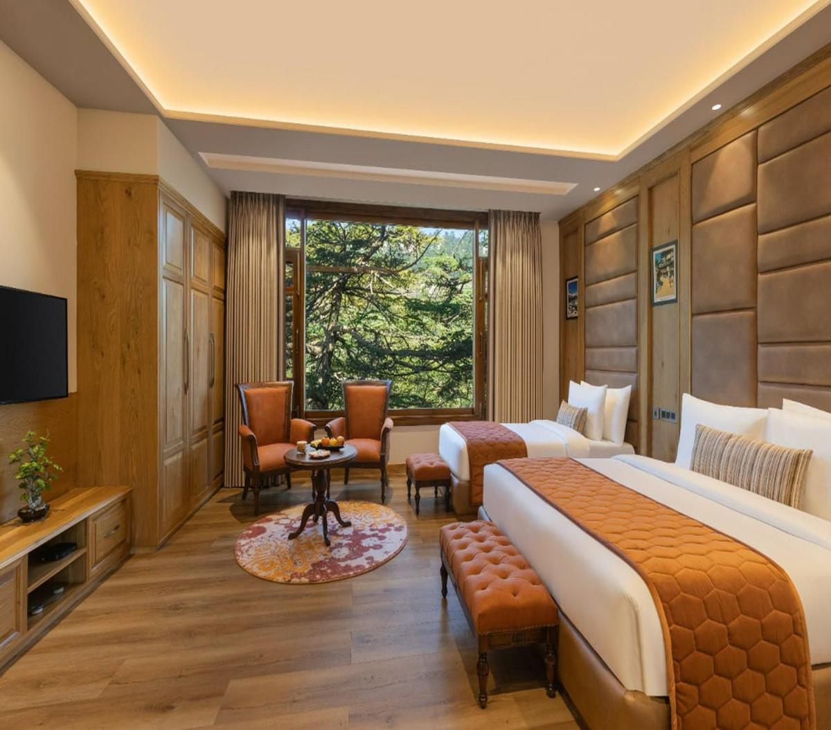 a hotel room with two beds and a television at WelcomHeritage Elysium Resort & Spa in Shimla