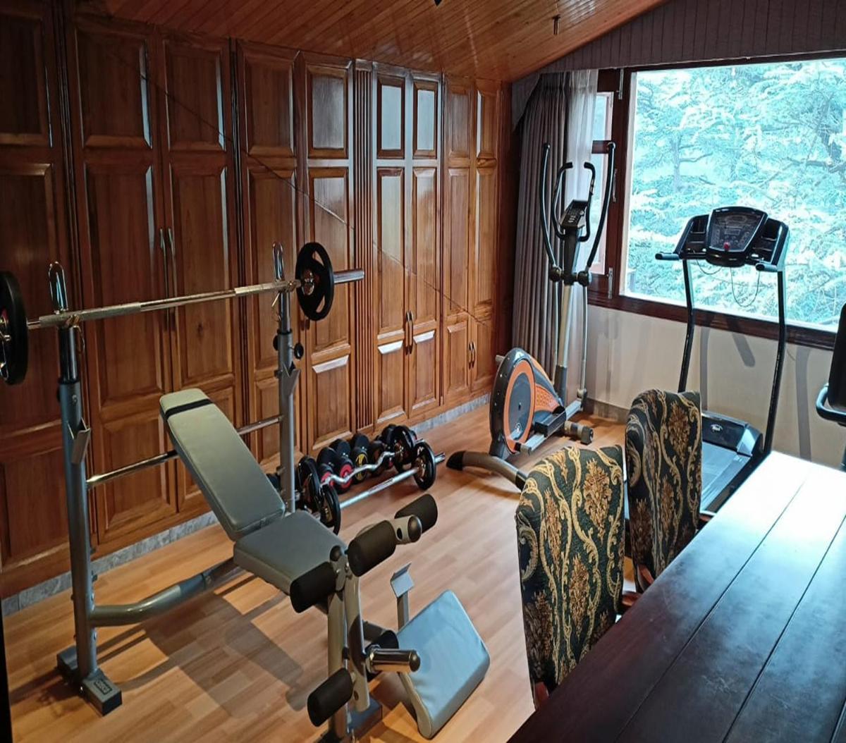 a room with a gym with a bench and weights at WelcomHeritage Elysium Resort & Spa in Shimla