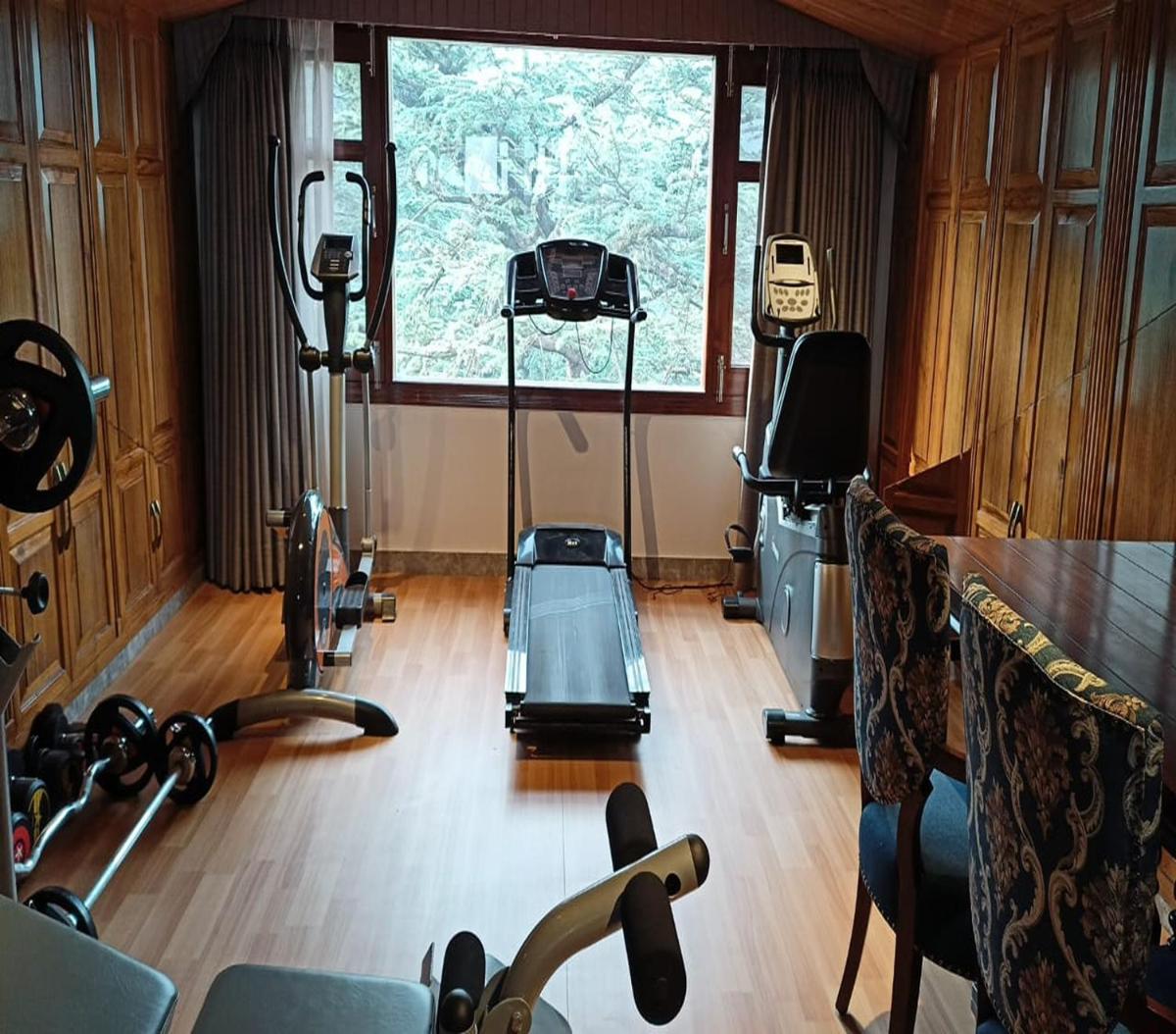 a room with a gym with a treadmill and a window at WelcomHeritage Elysium Resort & Spa in Shimla