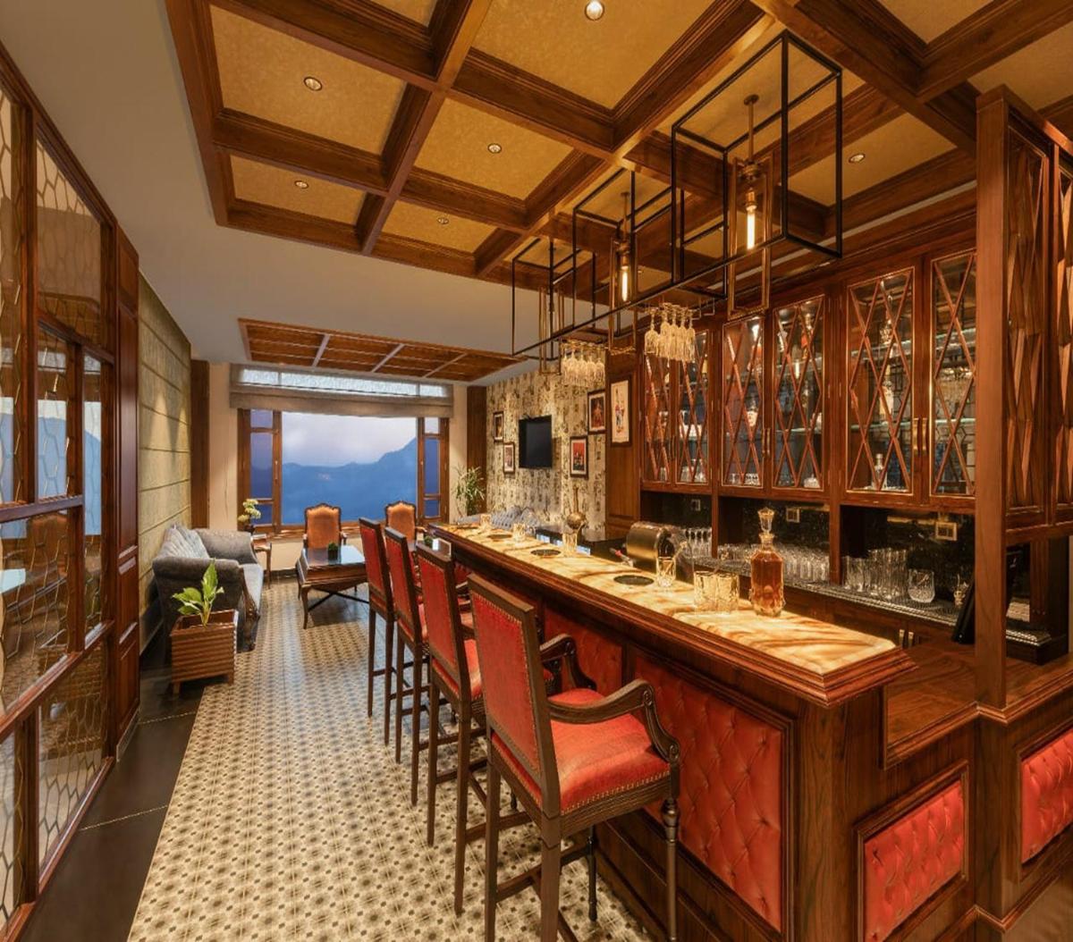 a bar with chairs and a counter with glasses at WelcomHeritage Elysium Resort & Spa in Shimla
