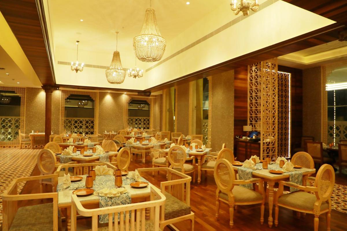 a restaurant with tables and chairs and chandeliers at Taj Tirupati in Tirupati
