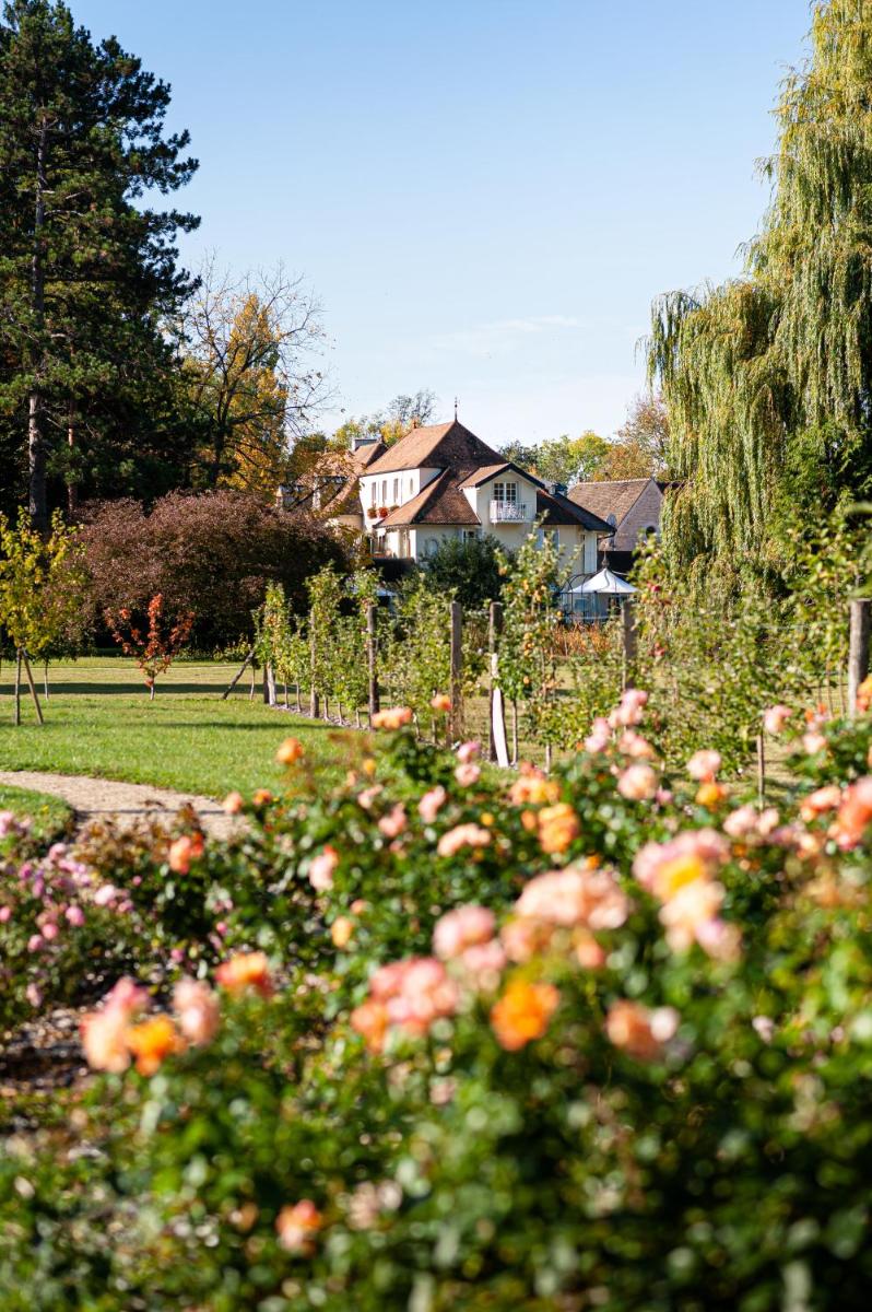 un jardin fleuri et une maison en arrière-plan dans l'établissement Hostellerie De Levernois, à Levernois